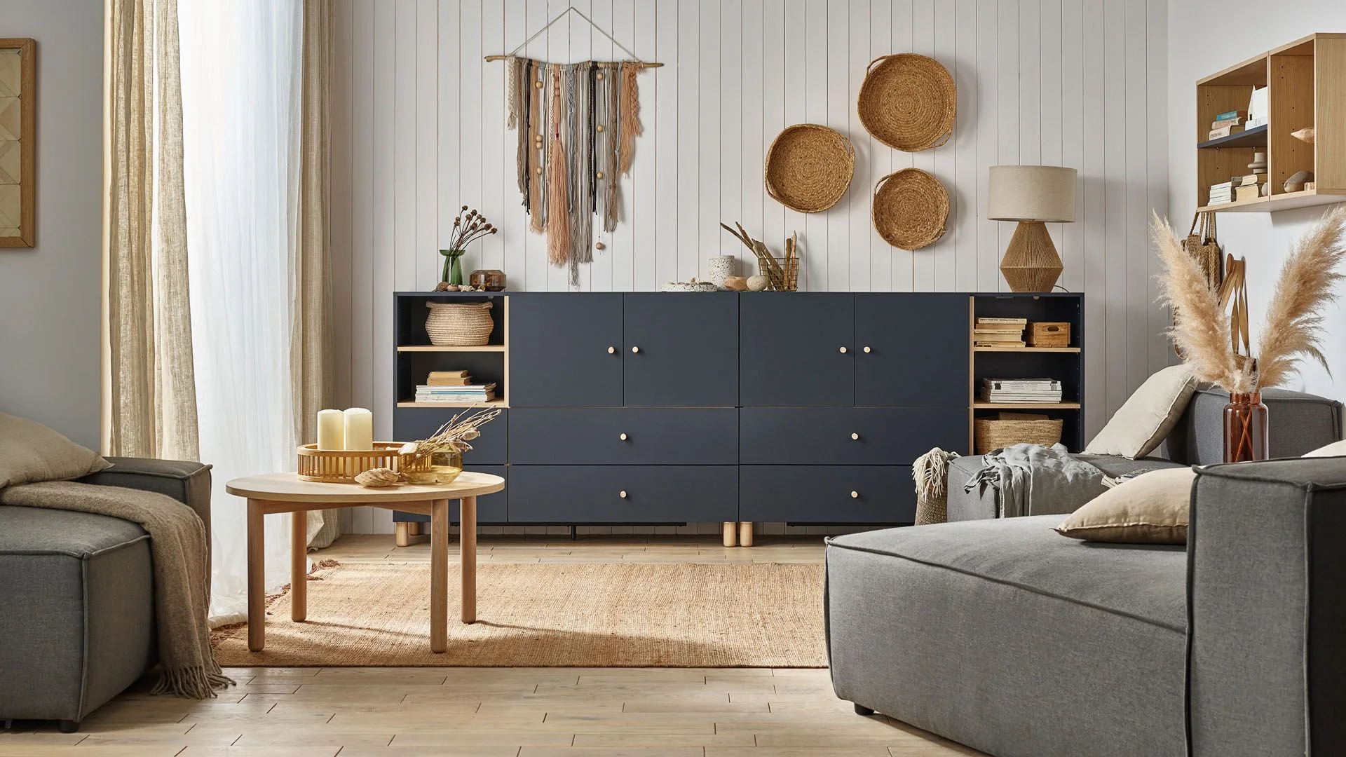 Salon z granatową komodą i naturalnymi dekoracjami w stylu boho.